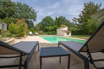 a swimming pool with two blue chairs and a table at Maison des lavandes in Saint-Cannat