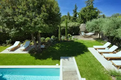 a yard with a swimming pool with lounge chairs and a yard at Le Clos des Rosiers in Gordes