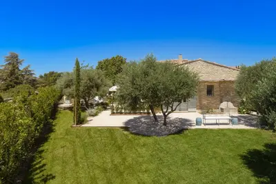 a garden with a bench and trees and a house at Le Clos des Rosiers in Gordes
