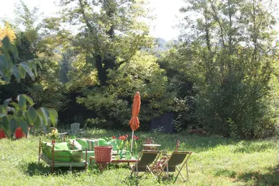 a table and chairs and an umbrella in the grass at La BARBELLA in Lourmarin