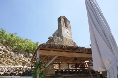 a clock tower on top of a building with a umbrella at La BARBELLA in Lourmarin