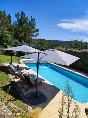 a pool with two chairs and an umbrella next to it at GITE AUX 4 SAISONS DU COLORADO PROVENÇAL - 3 ÉTOILES - Rustrel in Rustrel