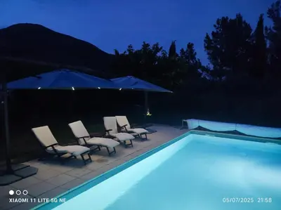 a swimming pool with chairs and umbrellas at night at GITE AUX 4 SAISONS DU COLORADO PROVENÇAL - 3 ÉTOILES - Rustrel in Rustrel