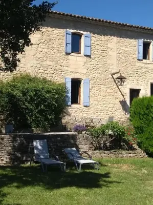 two chairs sitting in front of a stone building at Le Lavoir in Lacoste
