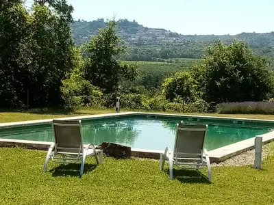 two chairs sitting in the grass near a swimming pool at Le Lavoir in Lacoste