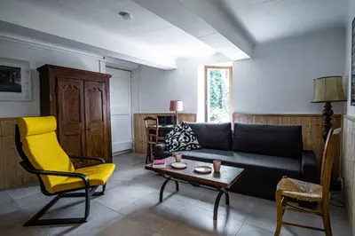 a living room with a black couch and a yellow chair at Maison en campagne avec vues panoramiques - close to a lake in La Tour-dʼAigues