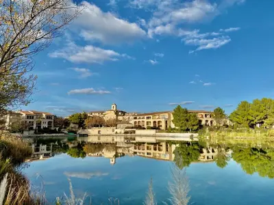 a view of a lake with buildings in the background at Maison de Vacances en Provence avec Piscine, Golf à Proximité, Fibre et Linge Haut de Gamme - FR-1-658-9 in Mallemort
