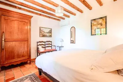 a bedroom with a bed and a wooden cabinet at Joli mas 