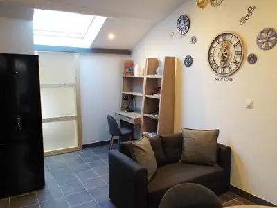 a living room with a couch and a clock on the wall at Appartement charmant à Avignon, 45 m² avec piscine partagée in Avignon