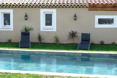 two chairs sitting by a swimming pool in front of a house at charming villa with heated pool, 14 people, located in aureille, near les baux de provence, in the alpilles in Aureille