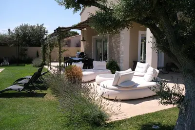 a patio with white couches and a table in a yard at charming villa with heated pool, 14 people, located in aureille, near les baux de provence, in the alpilles in Aureille