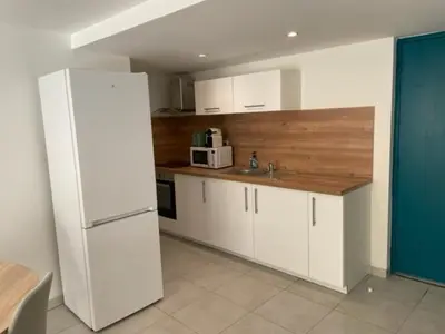 a kitchen with white cabinets and a white refrigerator at Appartement climatisé avec cour en centre ville in Carpentras