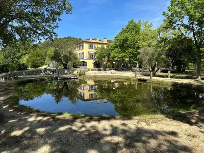 a pond in front of a large house at BASTIDE DU DEFENDS in Pertuis