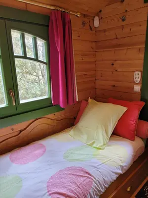 a bed in a log cabin with a window at La Roulotte des Oliviers in Saint-Pierre-de-Vassols