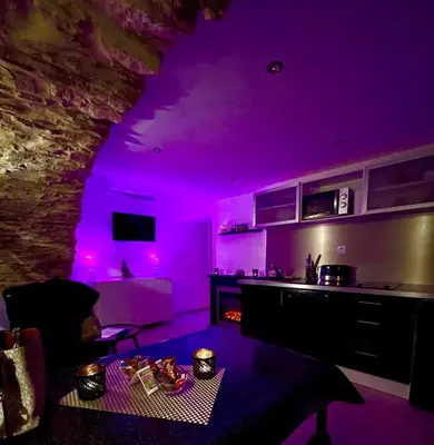a living room with purple lighting and a kitchen at Appartement Love room avec jacuzzi et hammam privatisé Lieu insolite en amoureux Spa détente assurée avec de doux massages en options sur demande in Orgon