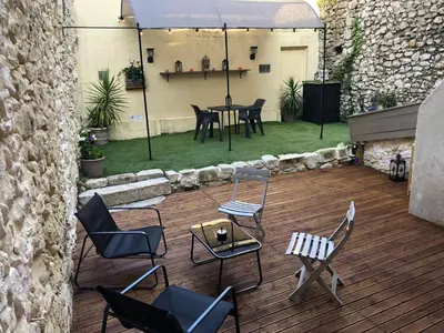 a patio with chairs and a table and an umbrella at Appartement Love room avec jacuzzi et hammam privatisé Lieu insolite en amoureux Spa détente assurée avec de doux massages en options sur demande in Orgon
