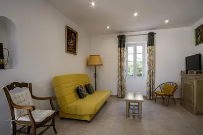 a living room with a yellow couch and a tv at Maison avec jardin proche du centre-ville Isle-sur-la-Sorgue in LʼIsle-sur-la-Sorgue