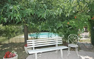 a white bench and a chair under a tree at Mas Mirasol in Gargas