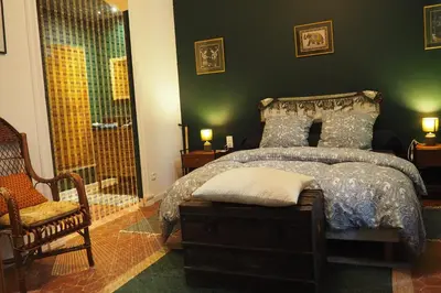 a bedroom with a bed and a chair and a window at Chambres d'Hôtes Le relais des marmottes en Luberon in Lagnes