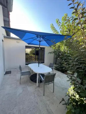 a table with a blue umbrella on a patio at Petite maison près du centre in LʼIsle-sur-la-Sorgue