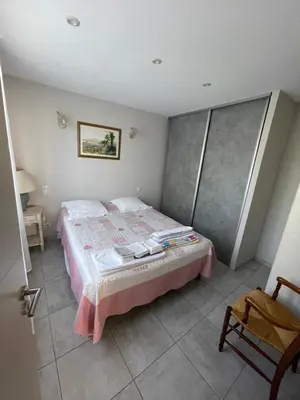 a bedroom with a bed and a chair in it at Petite maison près du centre in LʼIsle-sur-la-Sorgue