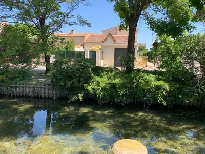 a house with a pond in front of a house at Petite maison près du centre in LʼIsle-sur-la-Sorgue