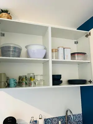 a kitchen cabinet filled with bowls and dishes at Un coin tropical en Provence ! in LʼIsle-sur-la-Sorgue
