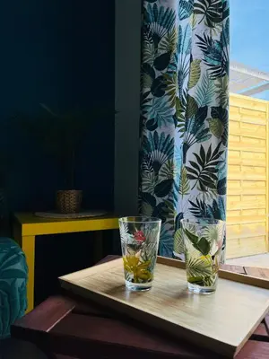 two glasses on a wooden table with a window at Un coin tropical en Provence ! in LʼIsle-sur-la-Sorgue