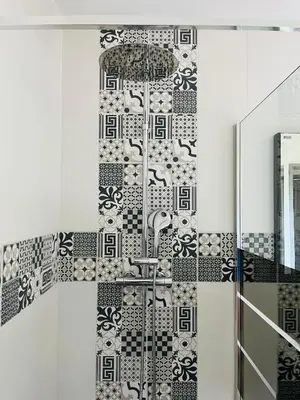 a bathroom with a black and white tile wall at Un coin tropical en Provence ! in LʼIsle-sur-la-Sorgue