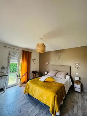 a bedroom with a large bed with a yellow blanket at Un coin tropical en Provence ! in LʼIsle-sur-la-Sorgue
