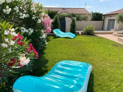 a garden with two blue chairs in the grass at Villa Provençale avec Piscine Chauffée in Saint-Andiol