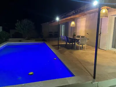 a swimming pool at night with a table and chairs at Villa Provençale avec Piscine Chauffée in Saint-Andiol