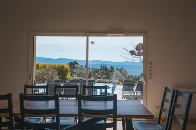 a dining room with a table and chairs and a large window at LE PETIT CHENE in Apt