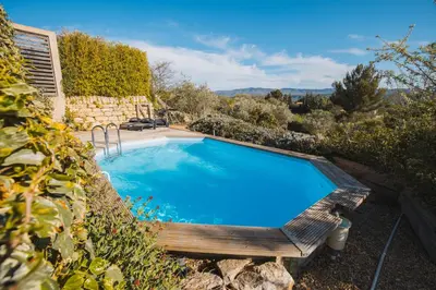 a swimming pool with a bench next to a house at LE PETIT CHENE in Apt