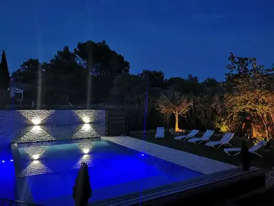a swimming pool at night with chairs and lights at Maison en provence vue sur le luberon in Maubec