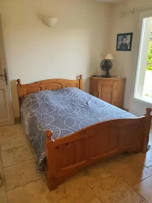 a bedroom with a wooden bed with a blue comforter at Villa L'Estagniol in Lourmarin