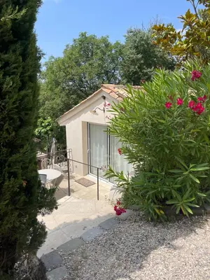 a house with a glass door and some pink flowers at Appart13 piscine chauffée de luxe Belvoir13 à 10 min d Aix in Aix-en-Provence