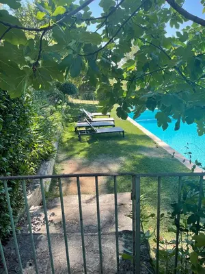 a couple of benches sitting on the grass next to a pool at Appart13 piscine chauffée de luxe Belvoir13 à 10 min d Aix in Aix-en-Provence
