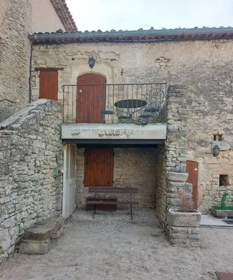a stone building with a bench on a balcony at Escapade romantique au cœur du Luberon, Piscine, calme et vue magique in Viens