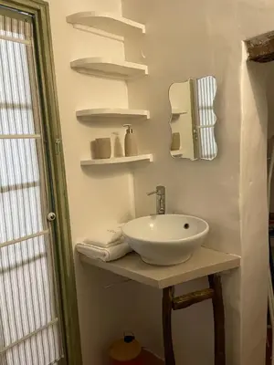a bathroom with a white sink and a mirror at Le Petit Egregore, patio et climatisation in Lauris
