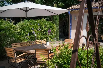 a table and chairs with an umbrella in a garden at L'Insoupçonnée Saint Rémy de Provence by A Pinch Of Soul in Noves