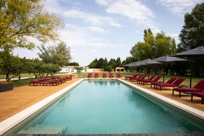 a swimming pool with red chairs and umbrellas at L'Insoupçonnée Saint Rémy de Provence by A Pinch Of Soul in Noves