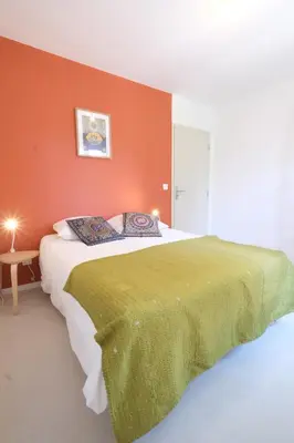 a bedroom with a large bed with an orange wall at superb villa with private pool, with magnificent view of the luberon, in the heart of provence, 8 persons in Puget