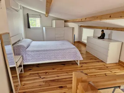 a bedroom with a bed and a wooden floor at Petite maison meublée entre Avignon et Carpentras in Morières-lès-Avignon