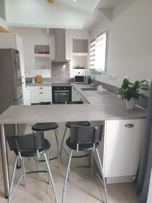 a kitchen with a counter and two stools in it at Petite maison meublée entre Avignon et Carpentras in Morières-lès-Avignon