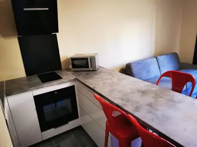 a kitchen with a counter with a microwave and red chairs at Appartement Indépendant dans le Résid hôtel idéal pour les vacances - séminaires - déplacements pro 