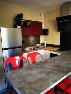a kitchen with red chairs and a counter top at Appartement Indépendant dans le Résid hôtel idéal pour les vacances - séminaires - déplacements pro 