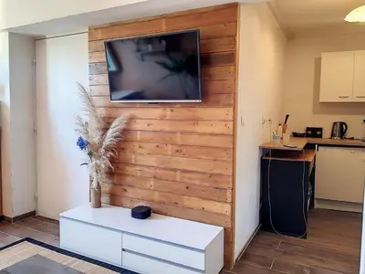 a living room with a wooden wall with a tv on it at Plein centre ville Appartement in Salon-de-Provence