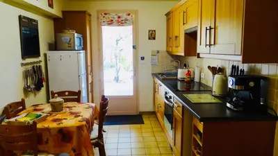 a kitchen with a table and a kitchen with a refrigerator at Gîte L'Escapade in Saint-Saturnin-les-Apt