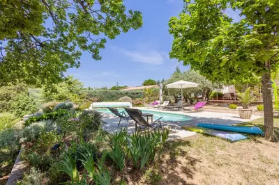 a backyard with a pool with chairs and a table at Gîte L'Escapade in Saint-Saturnin-les-Apt
